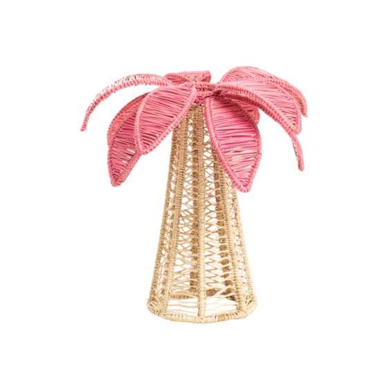 The Coro Cora Palm Tree Table Accent - Light Pink - Small features a handcrafted beige trunk and large pink leaves, creating a festive, decorative centerpiece. It's displayed against a plain white background.