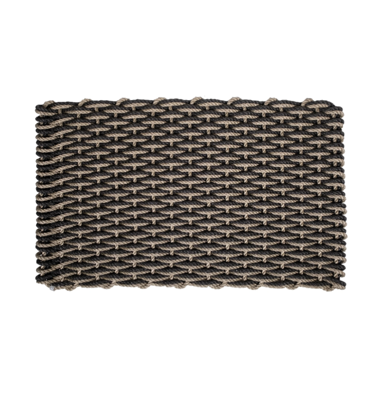 The Rope Co Coastal Woven Outdoor Floormat - Sand & Charcoal (24 x 38) features a sturdy, textured design crafted from thick black and beige ropes in a rectangular woven pattern, ideal for outdoor use. Shown on a white background.