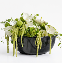 A Leona Bowl - Marina by CDMX / MASA TALLER, filled with white calla lilies, green amaranthus, viburnum, and other green and white flowers, is arranged elegantly against a white background to create a stunning decorative piece.