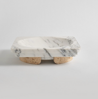 The Caldera Marble Bowl by Greg Natale features a rectangular design crafted from white marble with striking gray veining, elevated on three cork feet. Displayed against a plain white background, this elegant bowl effortlessly combines functionality with decorative appeal, bringing understated sophistication to any space.