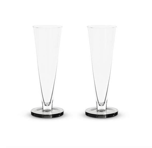Two empty, clear Tom Dixon Puck Flute Glasses (Set of 2) are standing side by side on a plain white background.