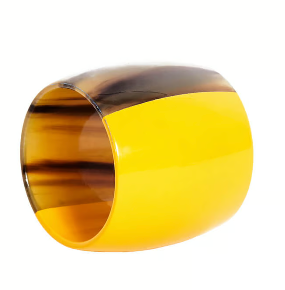 The Von Gern Home Horn Napkin Ring Set of 4 features bold split designs—bright yellow on one half, translucent brown tortoiseshell inspired by natural horn on the other—creating a striking look against any white table setting.