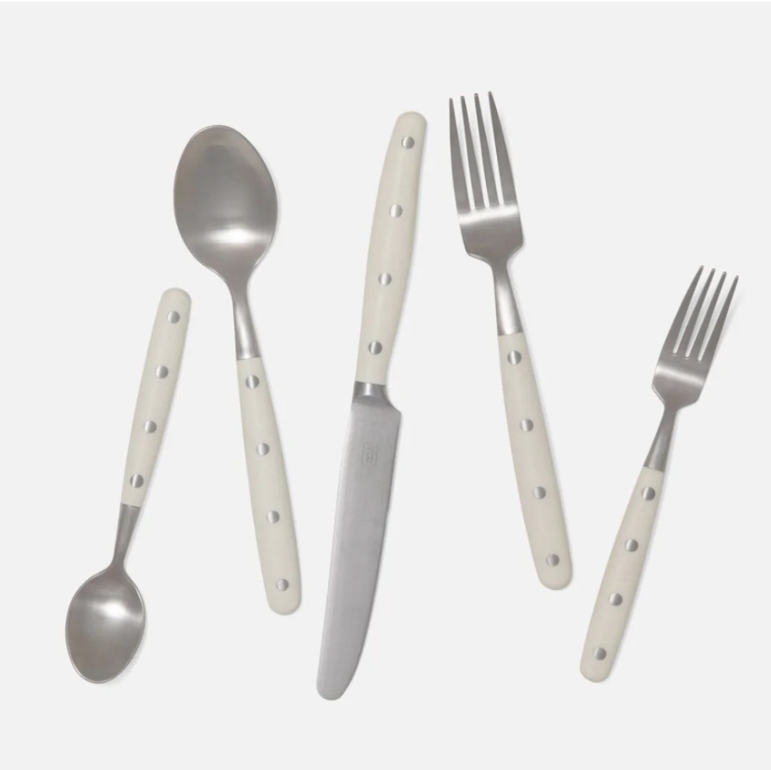 The Blue Pheasant Jones Flatware Ivory set includes five stainless steel pieces with white handles and three silver dots: small spoon, large spoon, knife, large fork, and small fork. All utensils are dishwasher safe.
