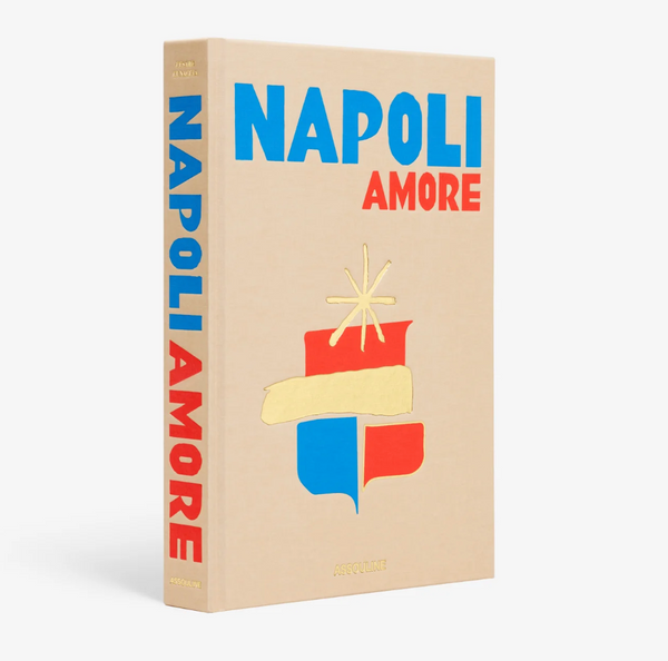 Napoli Amore by Assouline is a beige book with bold blue and red title text and a stylized gold, blue, red, and yellow emblem on the cover and spine, celebrating Neapolitan culture. The brand name appears at the bottom.