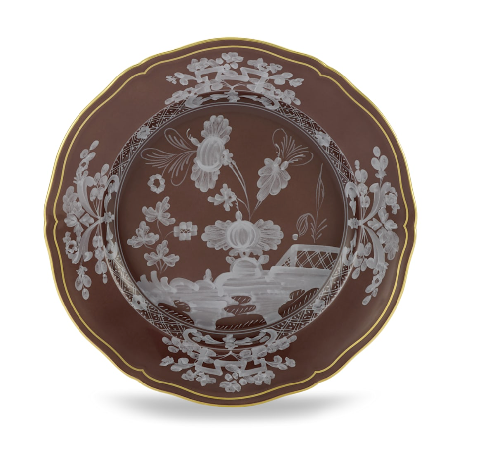 The Oriente Italiano Castagna plate by Ginori 1735 features intricate white floral and landscape patterns on brown with a gold-trimmed edge. Made in Italy, it's a decorative piece from the elegant Oriente Italiano Castagna tableware set.