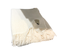 The Thread & Butter Waffle Alpaca Throw - Ivory is a cream-colored, sustainable alpaca blanket with a waffle texture, fringed ends, and a small tag, shown folded on a white background.