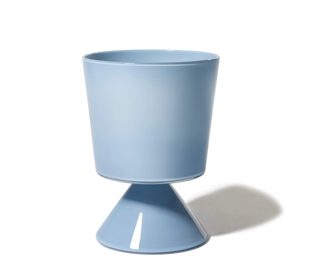 The Cariati Fiorelli Collection Vase - Dove features a modern, light blue ceramic design with a cylindrical top and cone base, ideal for pairing with sculptural glass vases. Shown on a white background with a soft shadow to the right.