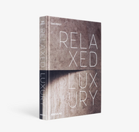 A hardcover copy of Relaxed Luxury by Assouline stands upright against a white background, its cover displaying elegant, minimalist text over a textured surface that reflects the brand’s sophisticated design style.