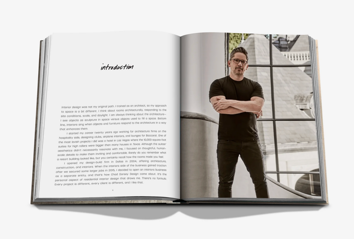 An open book, "Relaxed Luxury" by Assouline, displays an introduction on the left page and a photo of Chad Dorsey in a black t-shirt and glasses with arms crossed, standing in a modern, relaxed luxury interior on the right page.