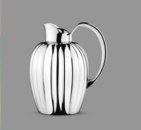 The Georg Jensen Bernadotte New Thermo Jug w/Push Stopper for coffee & tea features a polished silver finish, curved handle, and vertical ridges, showcasing modern Scandinavian style against a plain gray background.