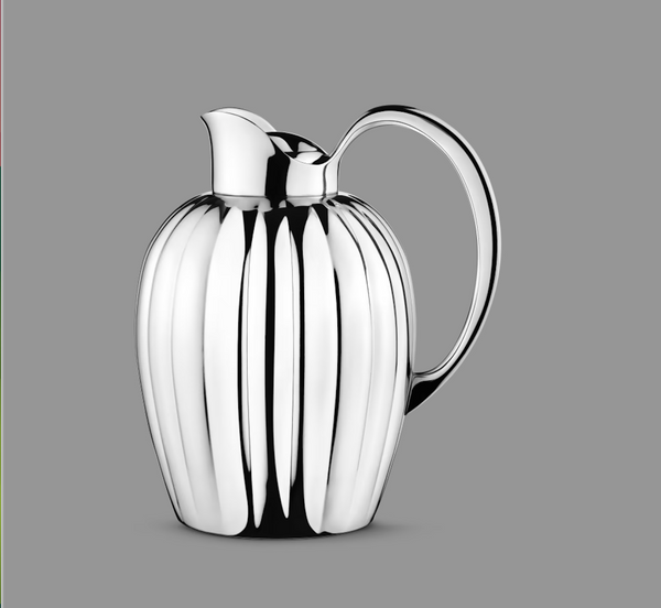 The Georg Jensen Bernadotte New Thermo Jug w/Push Stopper for coffee & tea features a polished silver finish, curved handle, and vertical ridges, showcasing modern Scandinavian style against a plain gray background.