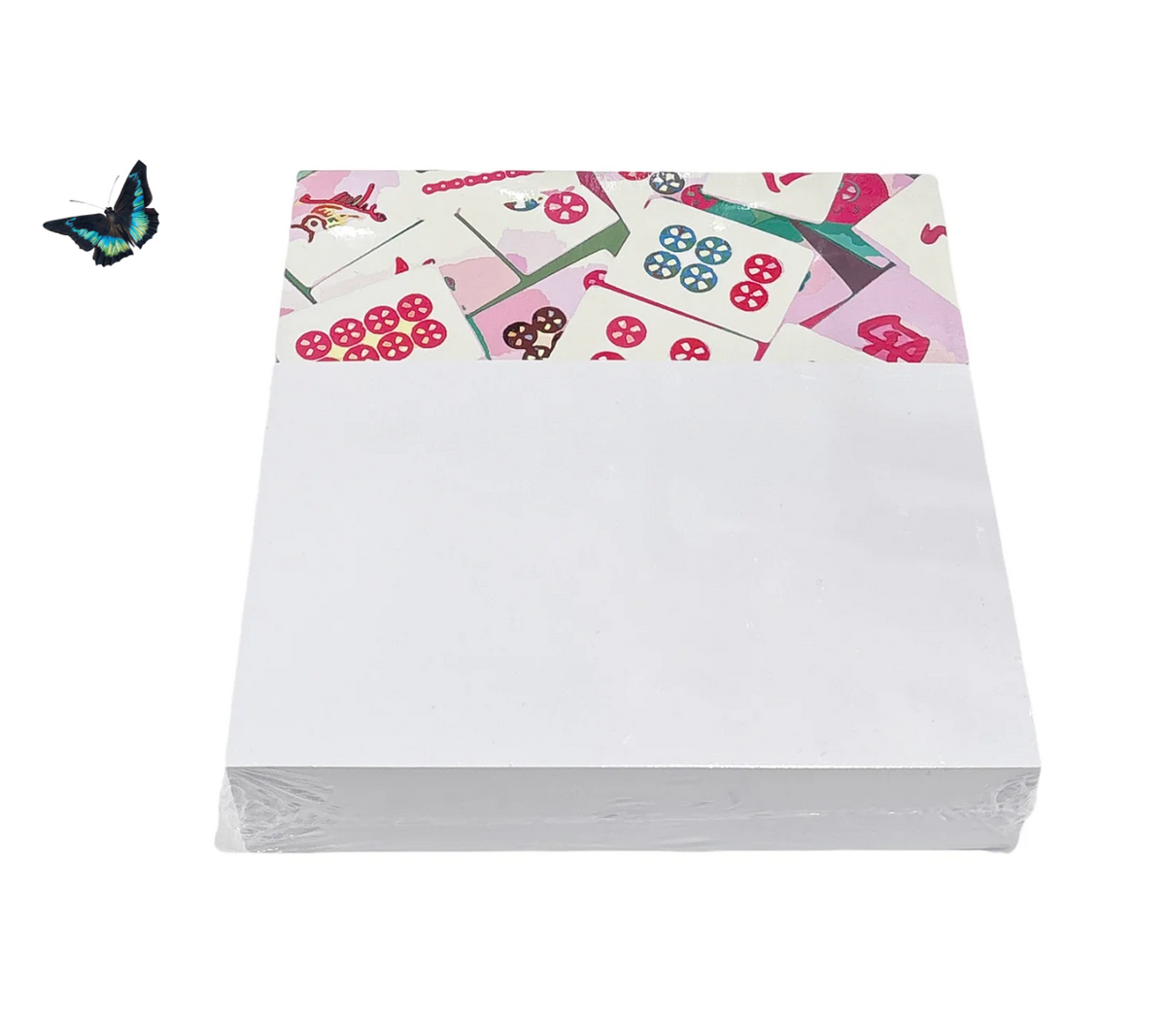 A stack of Mahjong Note Cards with Acrylic Holder by Nicolette Mayer, partially wrapped in tile patterns, is joined by a blue-black butterfly—making it a unique game night gift idea.