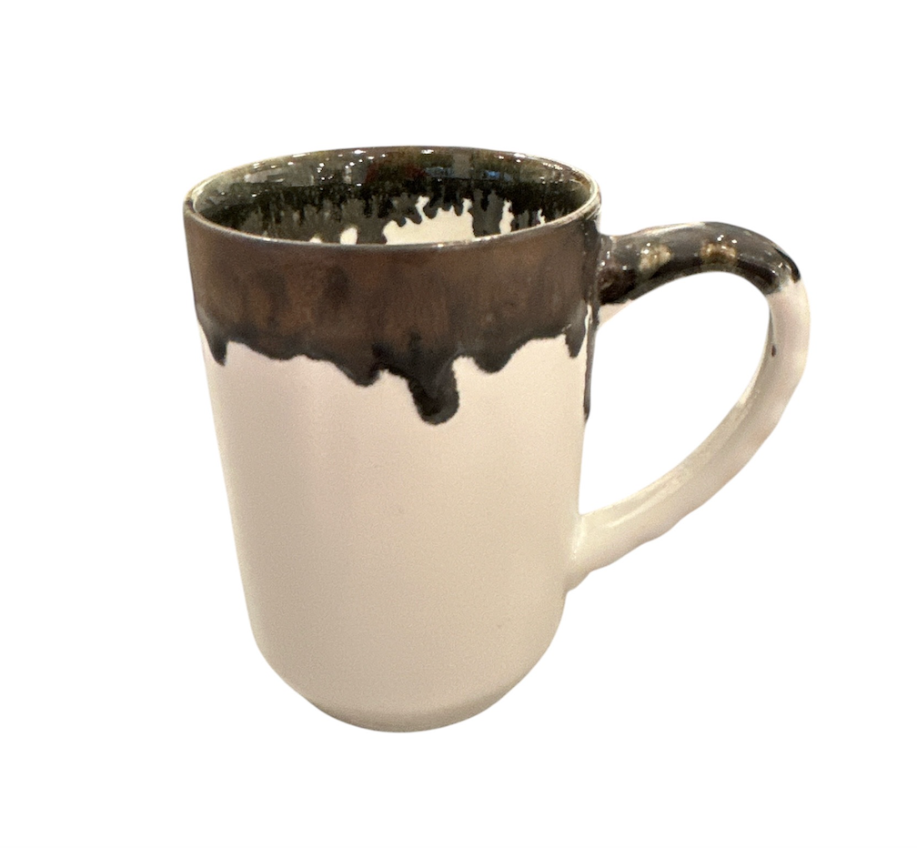 The Linea Dinnerware ceramic mug by Michael Wainwright features a white base with a dark brown, uneven glaze dripping from the rim onto the handle, set against a white background.