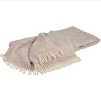 The Diana Mohair Throw by Mantas Ezcaray is a soft, folded light mauve blanket with white fringed edges, elegantly displayed on a white background.