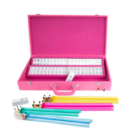 The Ellen Mahjong Set - Pink by Brouk & Co features a pink Saffiano vegan leather case filled with mahjong tiles, colorful betting sticks, dice, and racks—making this portable set both stylish and convenient.