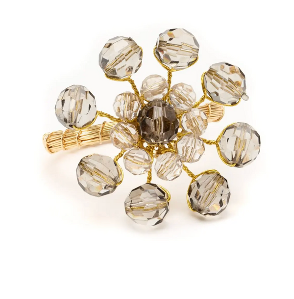 The Party Burst Beaded Napkin Ring Set of 4 by Deborah Rhodes features gold-tone bases adorned with faceted, translucent beads arranged as petals around a central bead, highlighting artisanal craftsmanship on a white background.