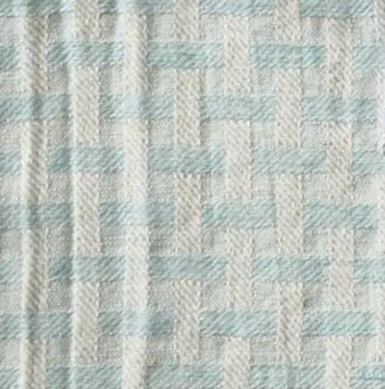 A close-up of the Deborah Rhodes Lattice Fringe Napkin Set of 4 shows a light blue and off-white basketweave pattern, featuring a textured, geometric design.