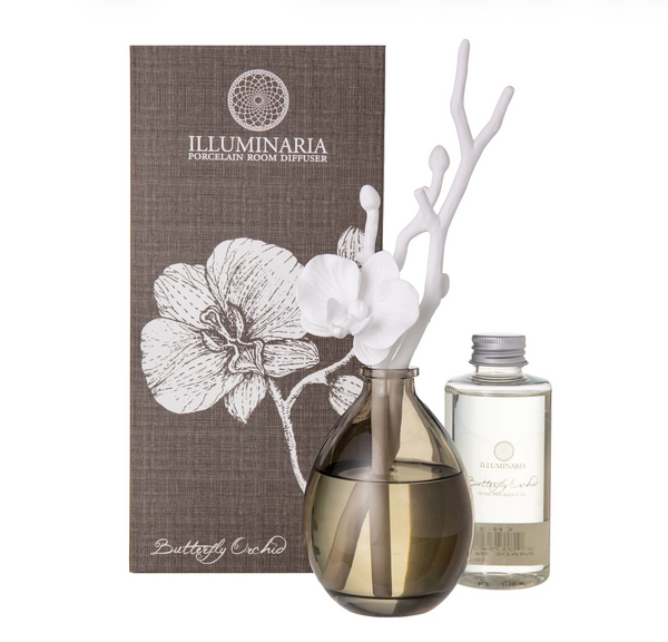 The Zodax Butterfly Orchid Diffuser features a smoky glass vase, white orchid-shaped diffuser sticks, fragrance oil, and comes in a decorative orchid-themed box.