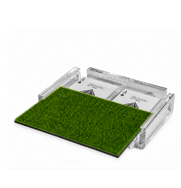 The Luxe Dominoes La Pinta Card Deck - Green Grass features two decks in a clear acrylic holder, partially covered by a rectangular piece of artificial grass.