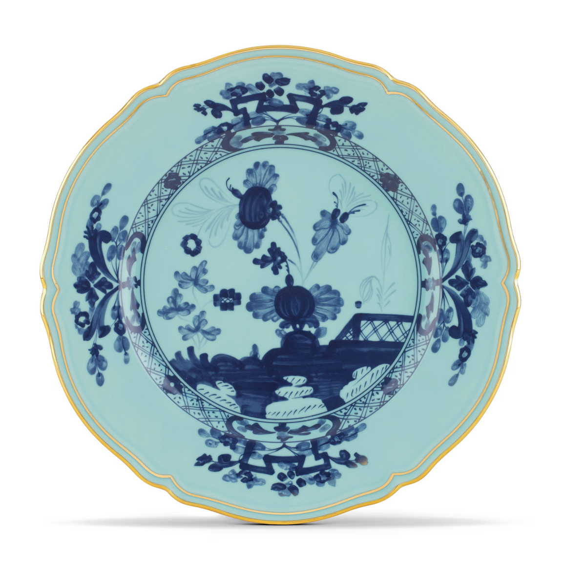 Oriente Italiano Dinnerware Iris by Ginori 1735: A porcelain plate with a scalloped gold rim, adorned with delicate chinoiserie-inspired floral and leaf patterns and a central landscape scene, all set against a light blue background.
