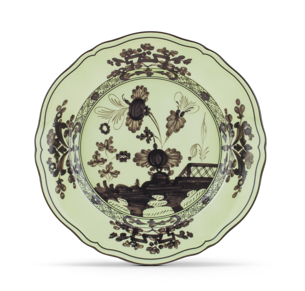 A scalloped-edge plate with a pale green background, adorned with intricate dark brown floral and landscape motifs around the center and border, this exquisite piece from the Ginori 1735 Oriente Italiano Dinnerware Bario collection captures the timeless elegance of classic chinoiserie design.