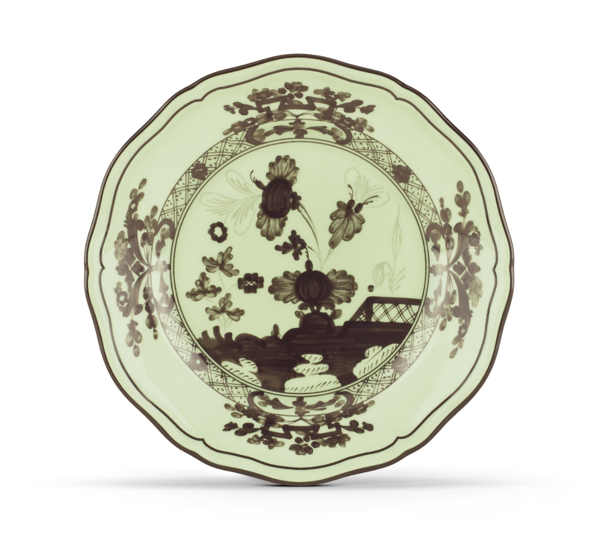 A decorative ceramic plate from Ginori 1735’s Oriente Italiano Dinnerware Bario collection, featuring a scalloped edge, a pale green background with dark brown floral patterns, and a bridge design in the center, inspired by classic chinoiserie.