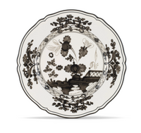 Oriente Italiano Dinnerware Albus by Ginori 1735 is a white plate adorned with an intricate black floral design featuring large flowers, leafy motifs, and a decorative border. Reminiscent of classic chinoiserie dinnerware, this plate showcases a scalloped edge and elaborate patterns throughout.