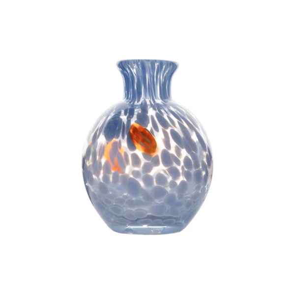 The Cello Spotted Bud Vase - Blue by Abigails is a round, transparent blue bud vase with a narrow neck, adorned with dappled white spots and accented by an orange oval near the center. Hand-blown in a Venetian-style, this vase highlights delicate craftsmanship and elegant design.