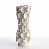 A tall, handcrafted vase from KleinReid’s Cumulus Collection Alabaster, featuring a matte white finish and adorned with large and small raised circular discs, set against a plain white background.