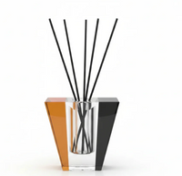 Experience the Frave Home Solar Prism Crystal Diffuser - Sapphire & Amber - Prosecco: a contemporary reed diffuser with black reeds, showcasing an angular crystal design in shades of orange, clear, and black against a white backdrop. This striking vessel beautifully disperses a refreshing Prosecco fragrance throughout your space.