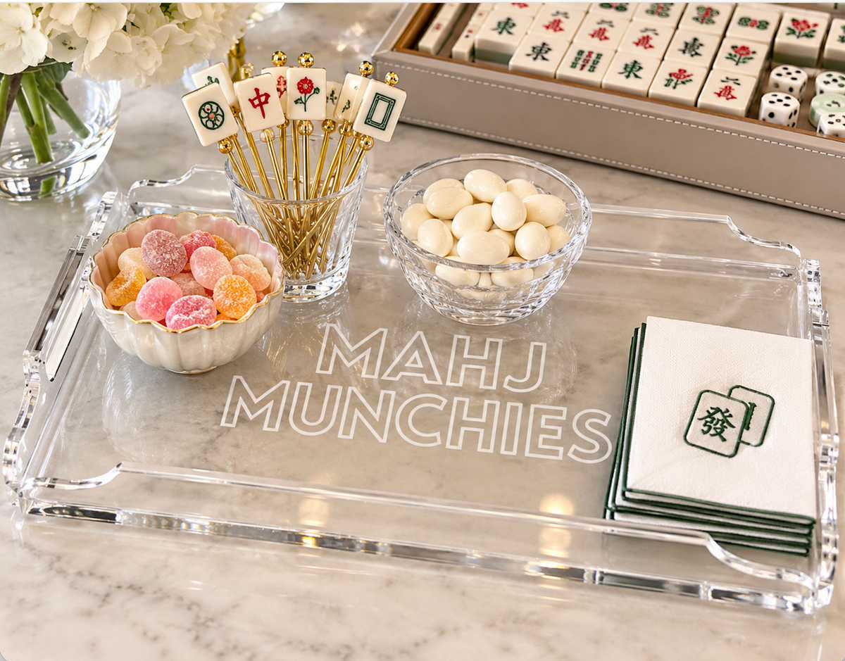 The Eye Candy Mahj Munchies Game Tray displays a bowl of colorful candy, white chocolate balls, decorative picks, and cocktail napkins with mahjong tiles and dice in the background.