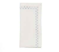 A folded Starry Night Napkin Set of 4 - White & Blue, featuring a blue metallic embroidery star pattern along the edge.