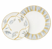 Two Marie Daâge Bouquet De Vie 1 dinnerware plates, one with hand-painted blue flowers and vines, the other with a gold and blue striped border, both featuring gold rims.