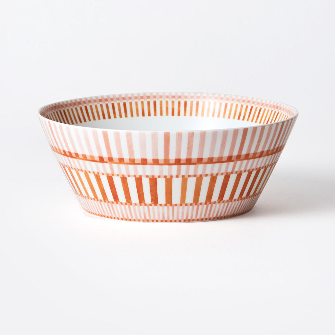 The Bernardaud Terra Rosa Dinnerware bowl features orange and pink vertical and horizontal stripes on a white background, showcasing the brand’s craftsmanship in an elegant ceramic piece set against a plain white surface.