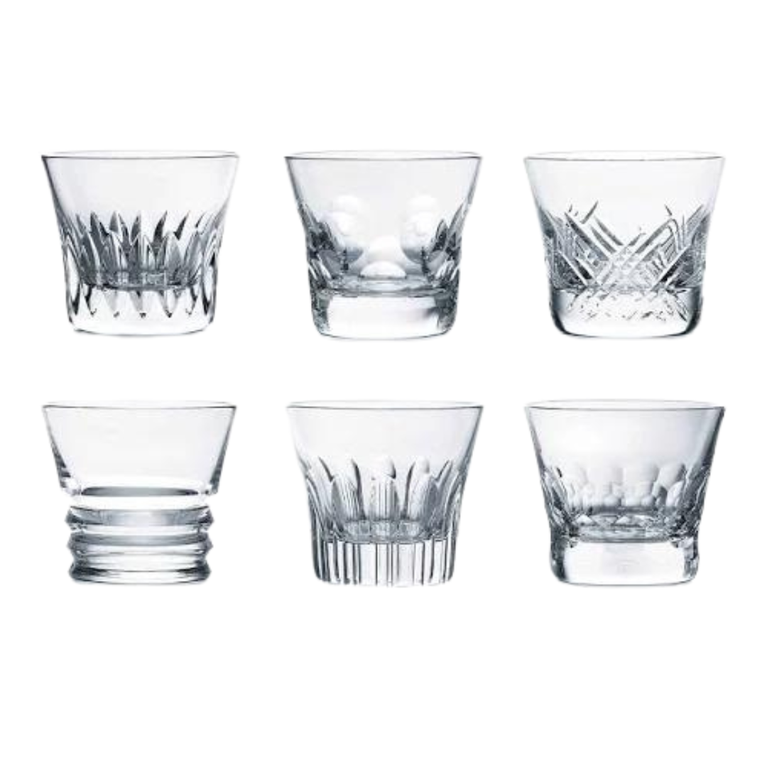 The Baccarat Everyday Tumblers Set of 6 features clear crystal glasses, each with a unique pattern, arranged elegantly—ideal for everyday use or gifting in a luxury box.
