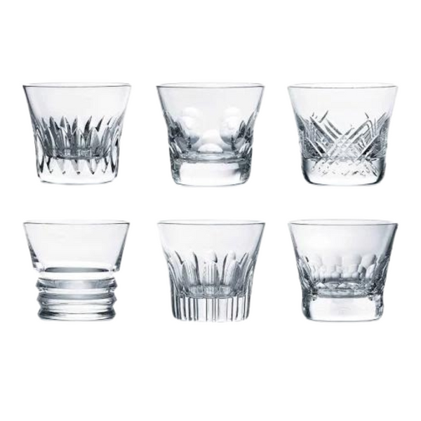 The Baccarat Everyday Tumblers Set of 6 features clear crystal glasses, each with a unique pattern, arranged elegantly—ideal for everyday use or gifting in a luxury box.
