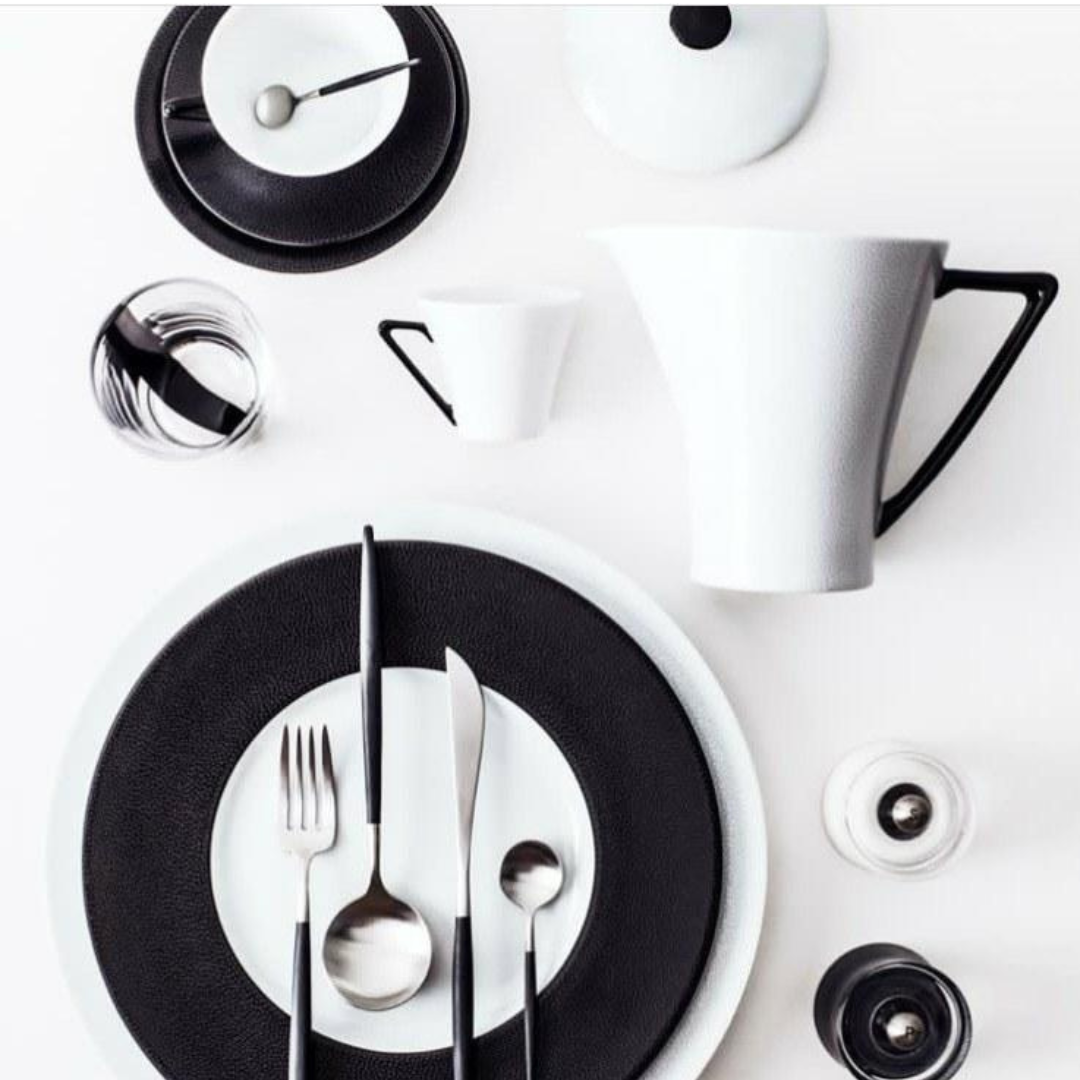 A minimalist table setting with Seychelles Dinner Plate Black 11" by Philippe Deshoulieres, crafted in fine Limoges porcelain, arranged on a white background.