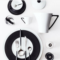 A minimalist table setting with Seychelles Dinner Plate Black 11" by Philippe Deshoulieres, crafted in fine Limoges porcelain, arranged on a white background.