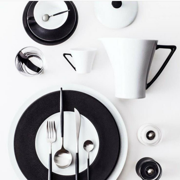 A minimalist table setting with Seychelles Dinner Plate Black 11" by Philippe Deshoulieres, crafted in fine Limoges porcelain, arranged on a white background.