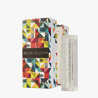A vibrant geometric box labeled Apeloig Collection sits beside a Modern Acrylic Mezuzah Case 4.5", containing a white decorative candle marked "INSTRUCTIONS," blending contemporary design with tradition.