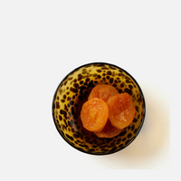 The Andrew Tortoise Nut Bowl by Blue Pheasant, featuring a brown and black speckled design, holds three dried apricots and is displayed against a plain white background.