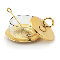 The Godinger Sphere Condiment Set Gold features a stylish bowl with a hammered gold-tone base, matching lid with circular handle, small gold spoon, and coordinating plate—creating an elegant serving arrangement with the lid tilted for easy access.