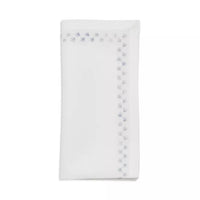 The Kim Seybert Starry Night Napkin Set of 4 in White & Blue features folded napkins with small light blue snowflake borders and delicate metallic embroidery along two edges.