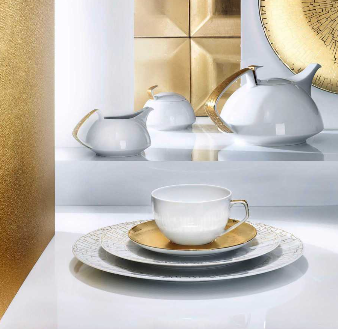 The Rosenthal Tac Skin Gold Dinnerware features elegant white porcelain with gold accents and durable glaze, including teacup, saucer, plates, teapot, creamer, and sugar bowl, displayed on a glossy white surface with gold decor.