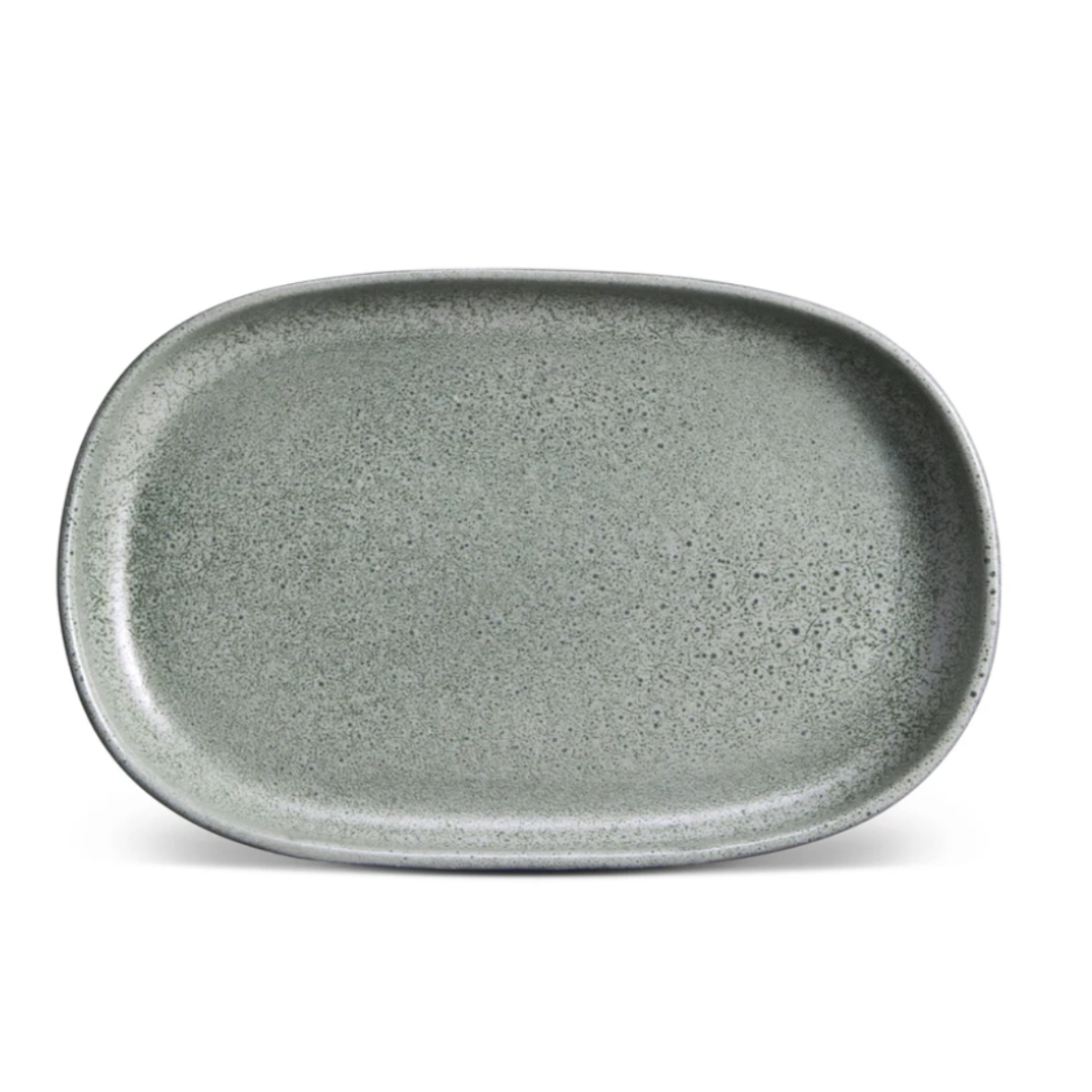 A large, oval-shaped ceramic plate from L'Objet’s Terra Seafoam Dinnerware, with a smooth, slightly speckled gray-green surface and rounded edges, shown from above on a white background.