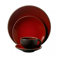 The Tourron Dinnerware Cerise by Jars - Rosenthal is a four-piece set in a deep red-black gradient, with round shapes and glossy glazes. Includes large and small plates, bowl, and cup with matching saucer. Dishwasher safe for easy cleaning.