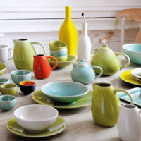 Tourron Dinnerware Eucalyptus ceramic collection, featuring bowls, plates, pitchers, and a teapot in various shapes and colors arranged on a table for modern everyday use.