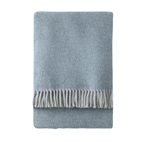 The A Soft Idea Tweed Weave Throw is neatly folded with a fringe along one edge and shown in light blue on a white background.