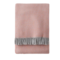 A Soft Idea’s Tweed Weave Throw, in folded soft pink with gray fringe trim, is neatly arranged on a white background.