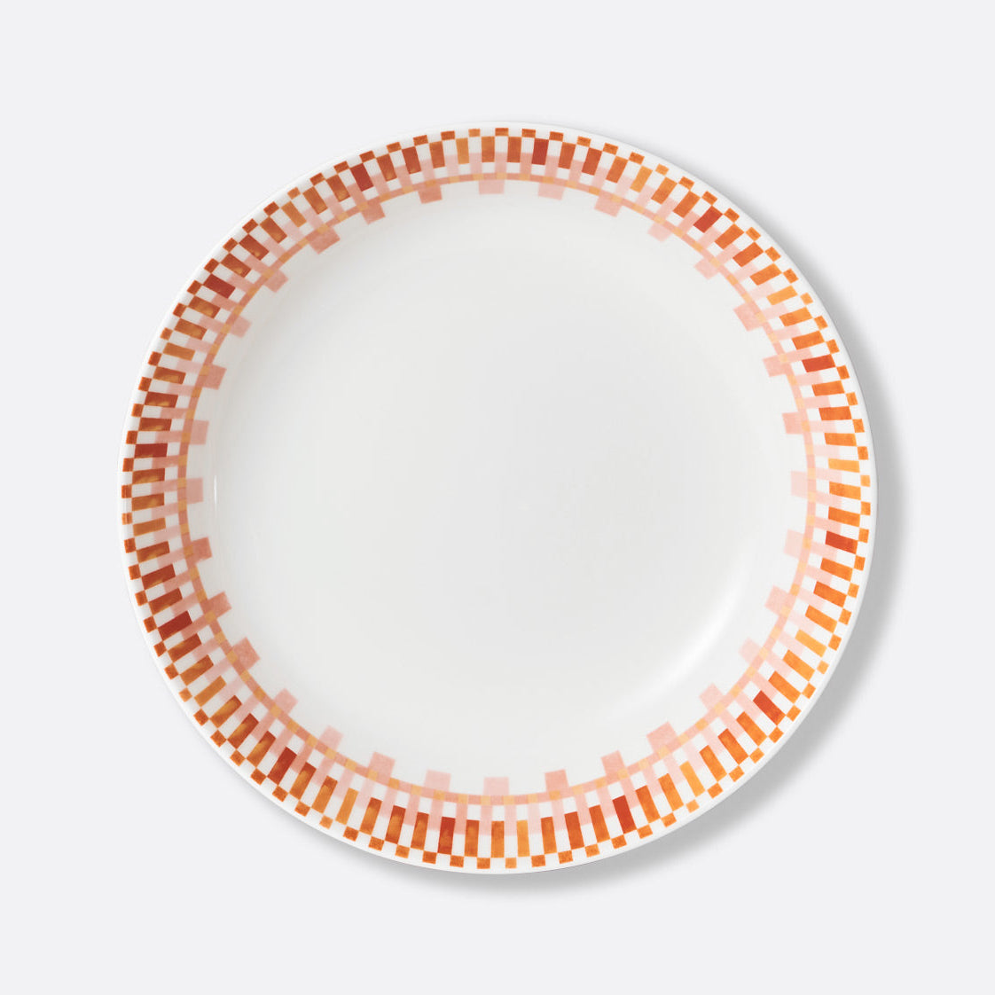 The Terra Rosa Dinnerware by Bernardaud features a white plate with orange and pink rectangle patterns encircling the rim. Made in Limoges, France.